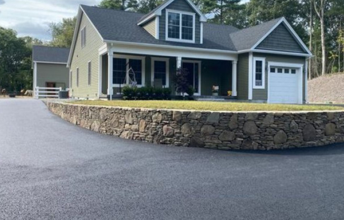 A house with a driveway and a stone wall.