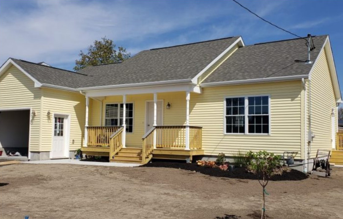 A yellow house with a porch and steps leading to the front.