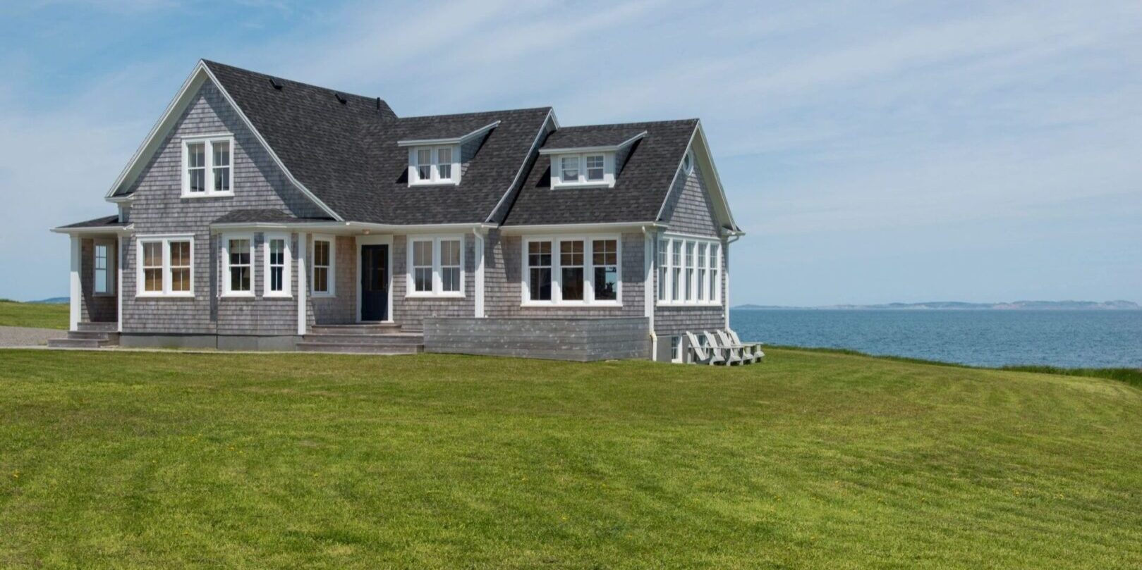 A house with grass and water in the background.