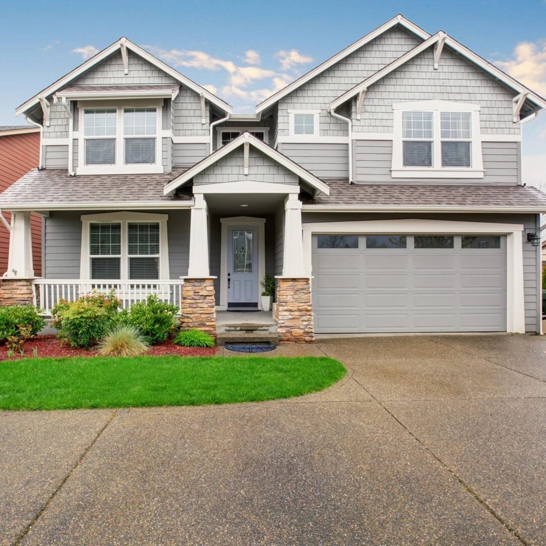 A house with a driveway and lawn in front of it.